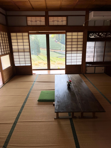 a traditional tatami room with wooden table and sliding doors, looking out onto matcha tea rows in Wazuka, Kyoto